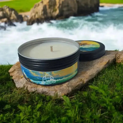 Tin candle with a seascape label on a rock by crashing waves, lid beside it