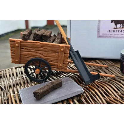 Miniature turf cart of turf sods and a turf spade on wicker, one sod on a slate in front, a white box behind