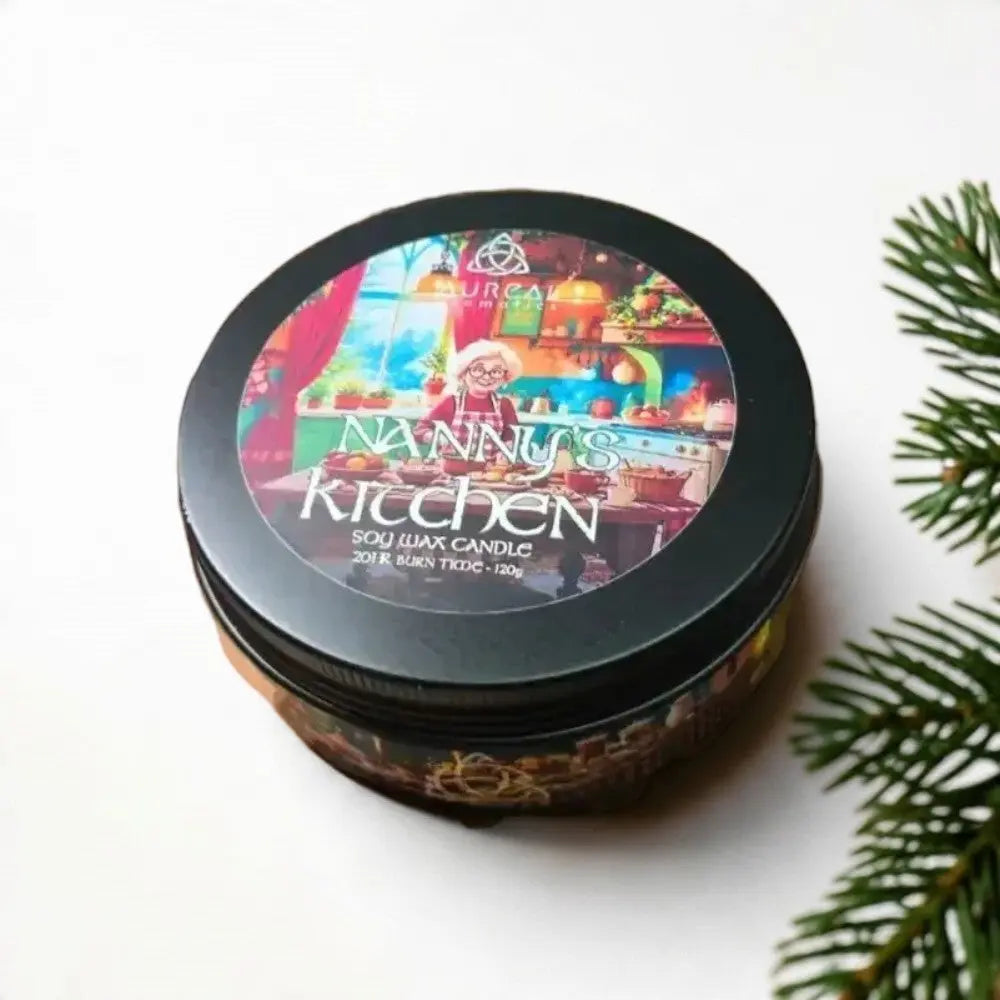 Nanny's Kitchen soy wax candle tin beside a pine branch
