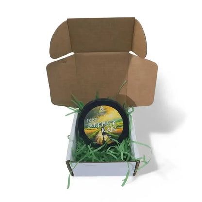 Irish Summer Rain candle tin in an open brown mailer box with green paper shred