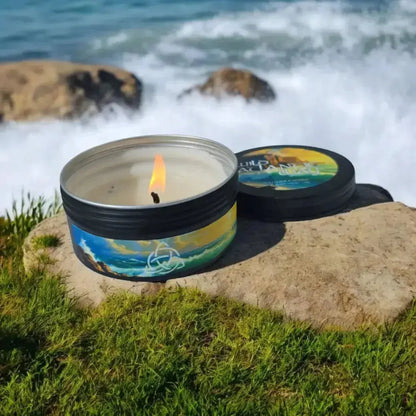 Lit Wild Atlantic Way tin candle on a rock with waves behind